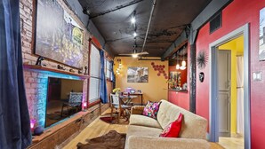 A cozy living room with a fireplace, a sofa, and a dining area. - Panther City Pad - Downtown Fort Worth (Fort Worth)