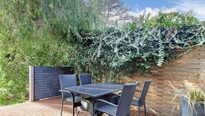 A wooden deck with a table and chairs, surrounded by a lush green hedge. - 2-bed Townhouse Retreat in Sandy Bay With Parking (Hobart)