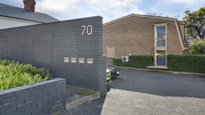 A building with a number '70' on a brick wall, a car parked in front, and a clear sky. - 2-bed Townhouse Retreat in Sandy Bay With Parking (Hobart)