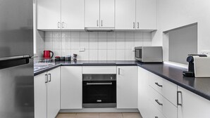 A modern kitchen with white cabinets, a stainless steel refrigerator, a built-in oven, and a microwave. - 2-bed Townhouse Retreat in Sandy Bay With Parking (Hobart)