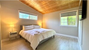 A bedroom with a bed, two bedside tables, a nightstand, a wooden ceiling, and two windows. - 3-bedroom house near Disneyland in Anaheim with AC (Anaheim)