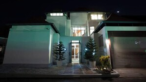Una casa moderna de dos pisos con una entrada bien iluminada, plantas en macetas y un garaje.