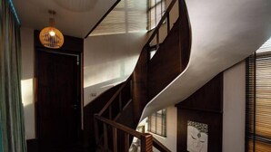 Una escalera de caracol con barandillas de madera y una lámpara colgante.