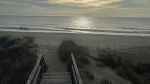 A wooden boardwalk leading to a beach with a cloudy sky and the sun visible near the horizon. - 1 Minute Walk To The Beach. Spectacular Ocean Views, Sun Rises, & Sun Sets! (Avon)