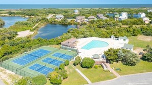 An aerial view of a residential area with a large swimming pool, tennis courts, and houses near a body of water. - 1 Minute Walk To The Beach. Spectacular Ocean Views, Sun Rises, & Sun Sets! (Avon)