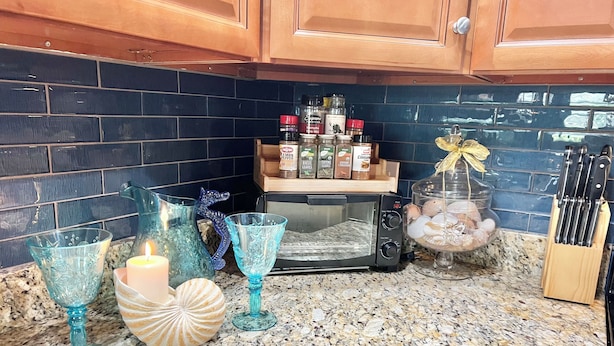 A kitchen with a granite countertop, a toaster, and various kitchen items like a candle, glassware, and spice jars.
