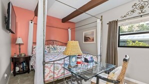 A bedroom with a bed, bedside table, lamp, and a window with curtains.