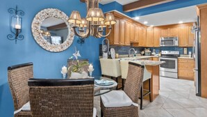 A kitchen with wooden cabinets, a central island, and a dining area with wicker chairs.