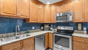 A kitchen with wooden cabinets, a stainless steel sink, a microwave, an oven, and a dishwasher.
