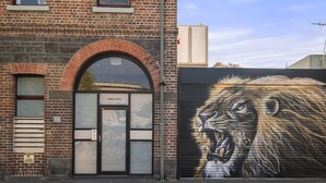 A brick building with a large mural of a roaring lion on the side.