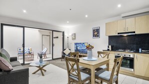 A modern kitchen with wooden cabinets, a dining area with a table and chairs, and a living room with a sofa and a coffee table.