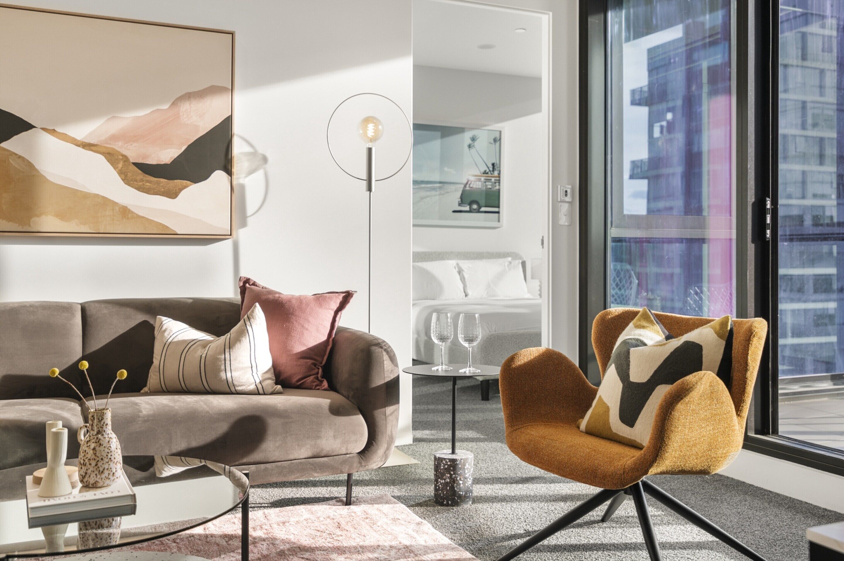 A modern living room with a sofa, armchair, coffee table, and a floor lamp.