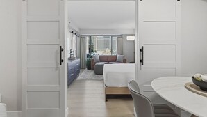 A bedroom with a bed, a desk, and a dining table. - SVS: Designer Tropical 1BD | Bellagio Fountain View | Resort Pool | Jockey Club (Las Vegas)