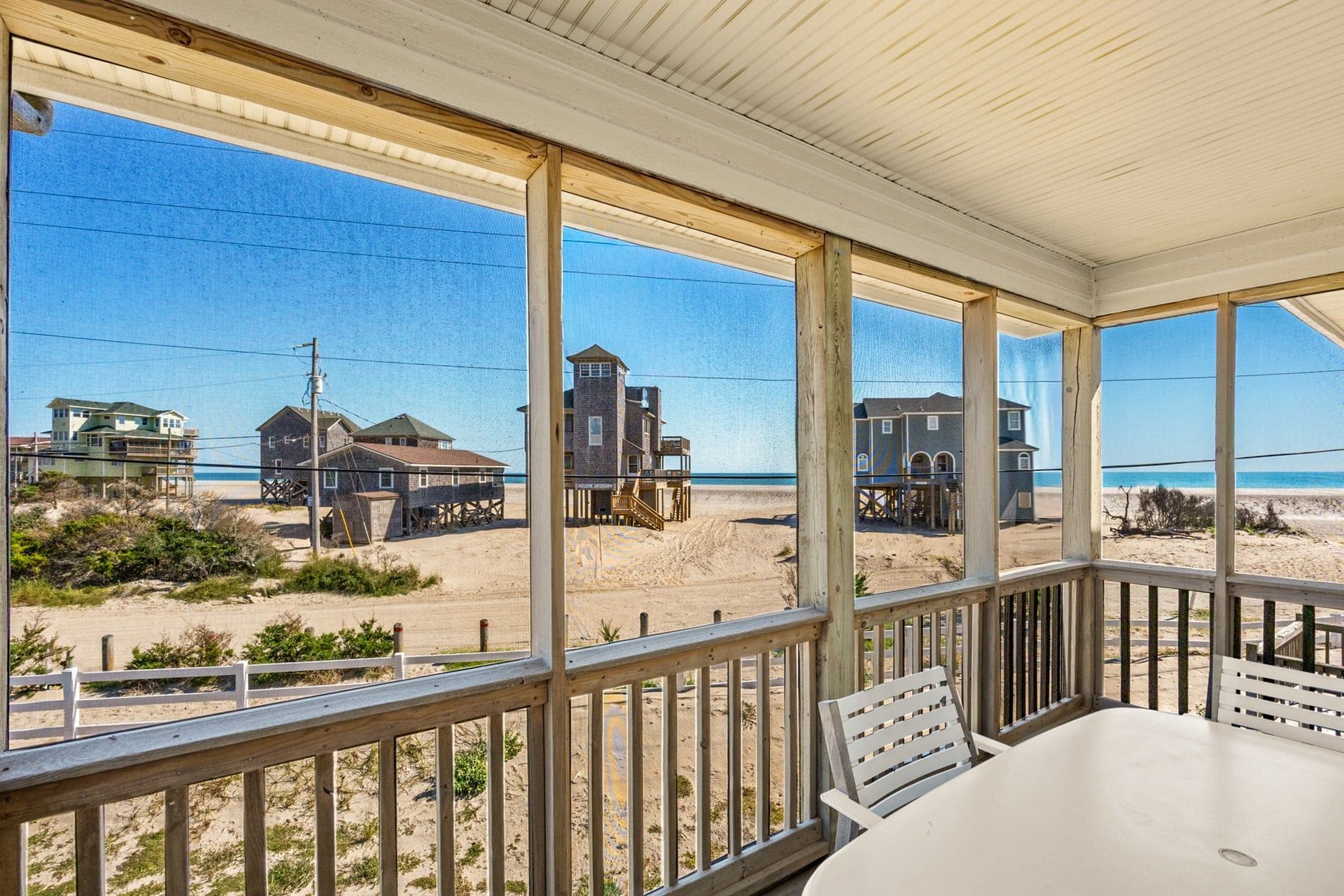A covered outdoor area with a view of a beach and buildings.