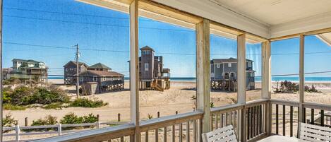 A covered outdoor area with a view of a beach and buildings.