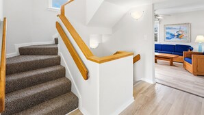 Eine Treppe mit hölzernen Geländern und Teppichstufen, die zu einem weißen Landeplatz führt.