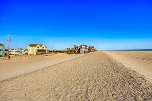 Une propriété située en bord de mer, comprenant plusieurs maisons, avec un ciel dégagé et une plage de sable.