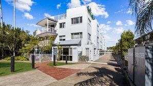 A modern multi-story building with a flat roof, a covered entrance, and a visible address number. - Spacious Esplanade Apartment With Rooftop Access (Hervey Bay)