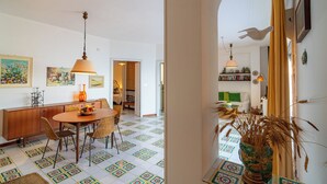 A dining area with a table and chairs, a hanging lamp, and a patterned floor. - Sea Escape - Apartment by the Sea (Giardini Naxos)