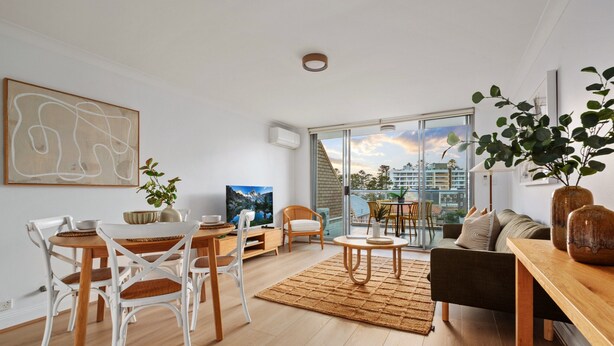 Uma sala de estar moderna com área de jantar, janelas amplas e vista para edifícios.