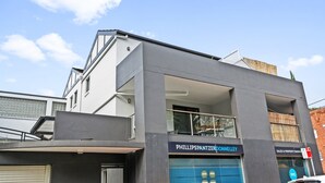 A modern building with a sign for 'PHILLIPSPANTZER DONNELLEY' and 'SALES & PROPERTY MANAGEMENT'. - Lovely 2-bed With Balcony (Sydney)