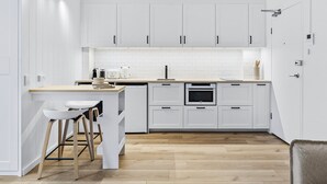 A modern kitchen with white cabinets, a wooden countertop, and a built-in oven. - Studio4: Bondi Chic Interiors With Rooftop Pool (Sydney)