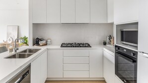 Eine moderne Küche mit weißen Schränken, einem Gasherd, einem Backofen und einem Geschirrspüler.