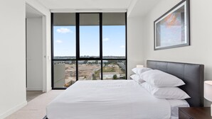 A bedroom with a large bed, a view through a sliding door, and a framed artwork on the wall. - Luxe 2-bed: Modern Interiors, Balcony & BBQ Area (Sydney)