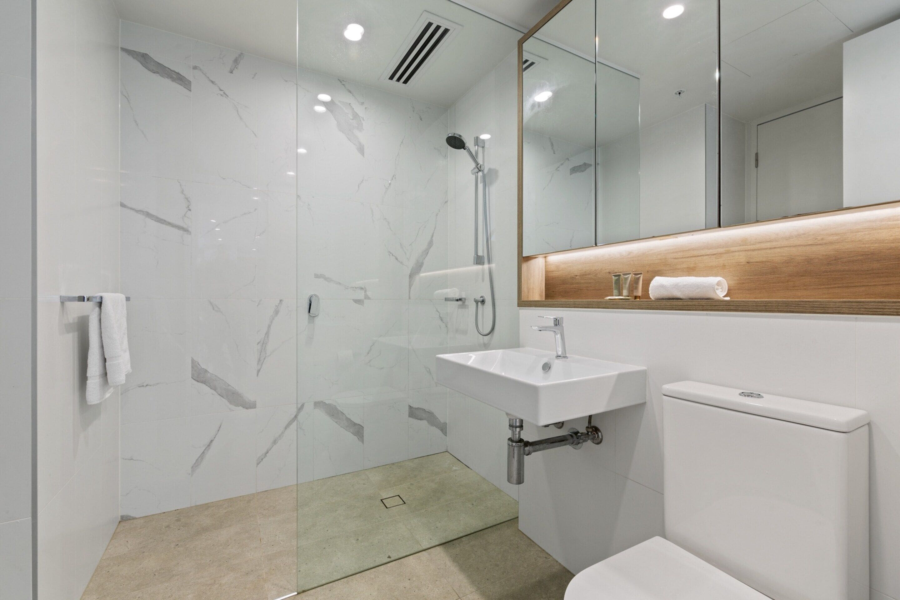 A modern bathroom with a shower, sink, and toilet.