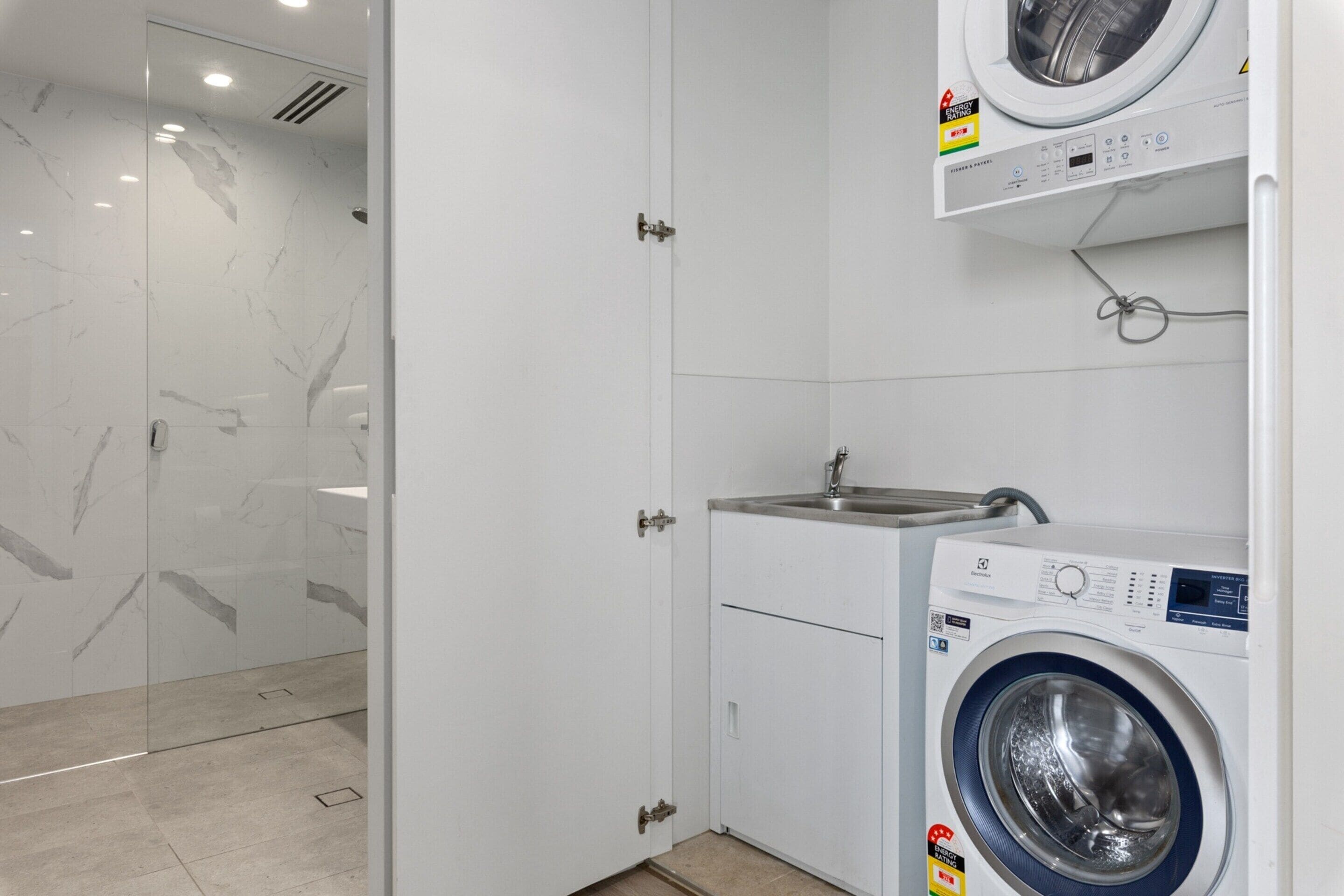 Un bagno moderno con box doccia in vetro, lavatrice integrata e lavandino.