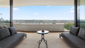 A balcony with a sofa, a small round table, and a view of a cityscape. - Luxe 2-bed: Modern Interiors, Balcony & BBQ Area (Sydney)