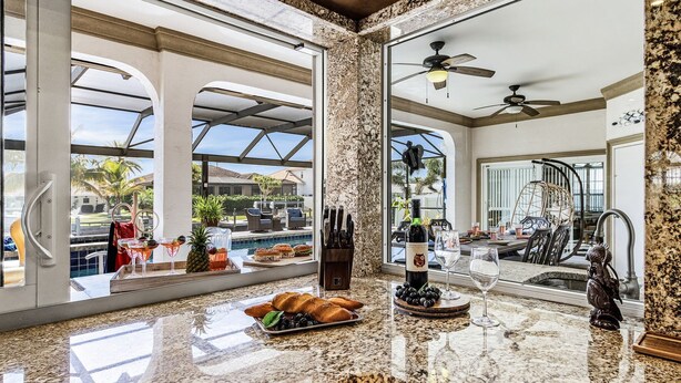 Una cocina con encimera de mármol, una botella de vino y una copa.