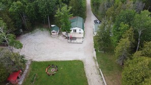 A property with a gravel driveway, a fenced yard, and a small circular seating area. - Lakefront 2-BR Cottage Retreat in Kagawong - Lilly Lakehouse (Billings)