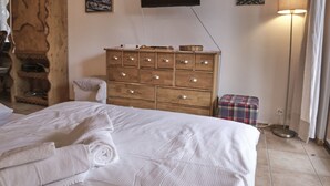 A bedroom with a large bed, wooden dresser, and a flat-screen TV on the wall. - Studio Pierre a Voir 4 (Riddes)