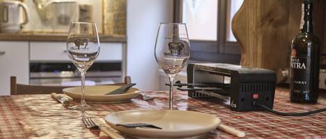 A dining table with two wine glasses, plates, cutlery, and a bottle of wine.