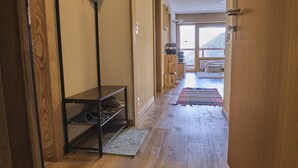 A hallway with wooden flooring, a shoe rack, and a door leading to a room with a view of a mountain. - Cosy Apartment in the Centre of Town With Views and Parking (Riddes)