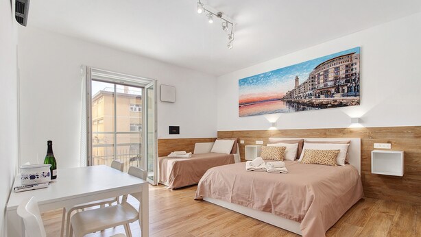 A hotel room with two beds, a dining table, and a painting on the wall.