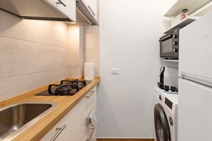 A compact kitchen with a gas stove, a microwave, a built-in oven, and a washing machine.