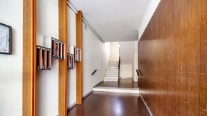 A hallway with wooden paneling, a staircase, and a framed notice on the wall.