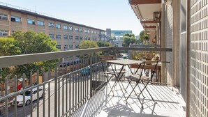 A balcony with a view of a cityscape, including buildings and trees.