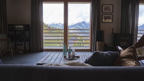A cozy living room with a large window offering a view of mountains. - Beautiful Luxury Chalet Veyon With Incredible Views (Riddes)