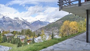 A mountain village with traditional wooden houses, a stone pathway, and a view of snow-capped mountains. - Beautiful Luxury Chalet Veyon With Incredible Views (Riddes)