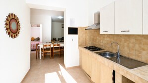 Cozinha com armários brancos, pia de aço inoxidável e backsplash revestido de azulejos.