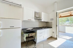 Una cocina moderna con armarios blancos, estufa a gas, horno empotrado y salpicadero de azulejos.