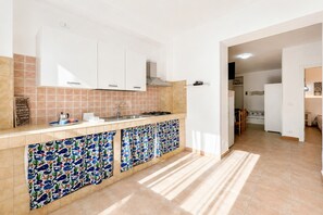 Une cuisine avec des meubles blancs, un dosseret carrelé et un autre dosseret décoré d’un motif.