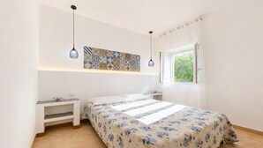 A bedroom with a bed, nightstands, a wall-mounted shelf, a window, and a patterned artwork. - Apartment 'Francesca, Trilo A' with Shared Terrace, Wi-Fi and Air Conditioning (Peschici)