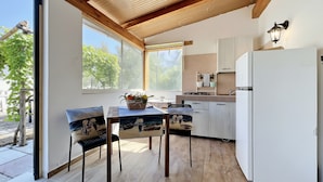 A modern kitchen with wooden beams, a white refrigerator, and a dining area with chairs and a table. - Studio Apartment 'Francesca, Mono Standard A' with Shared Terrace, Wi-Fi and Air Conditioning (Peschici)