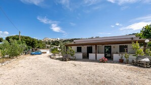 A building with a gravel driveway, a parked car, and potted plants. - Studio Apartment 'Francesca, Mono Standard A' with Shared Terrace, Wi-Fi and Air Conditioning (Peschici)