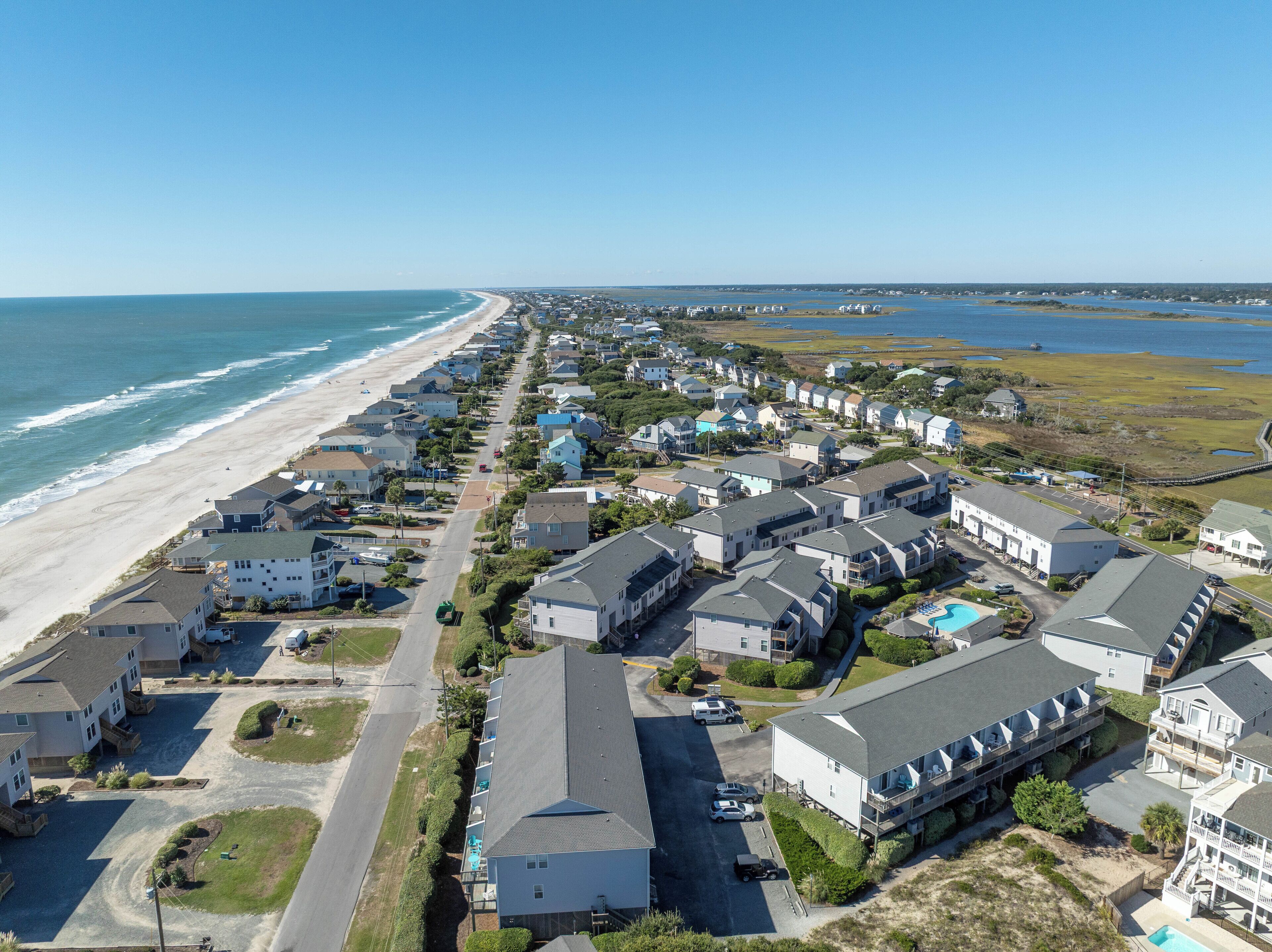 A coastal residential area with houses along the beach, a clear sky, and a view of the ocean.