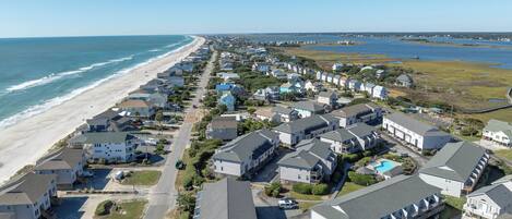 A coastal residential area with houses along the beach, a clear sky, and a view of the ocean.